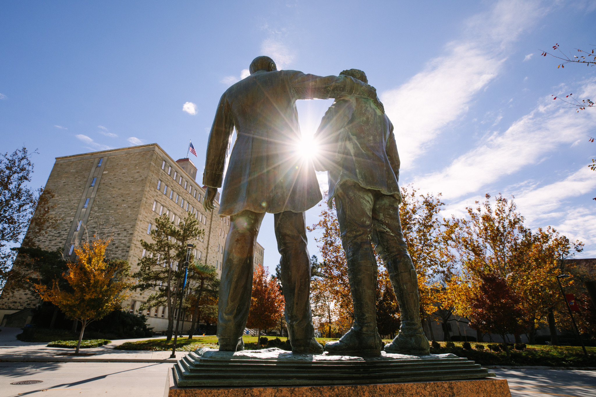 Statues facing Frasier Hall with sunlight coming through